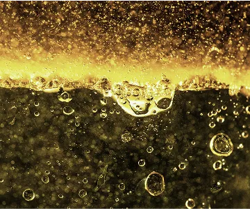 Close-up abstract image of golden bubbles in liquid texture, representing hydration, energy drinks, beverage freshness, antioxidant supplements, and wellness products.