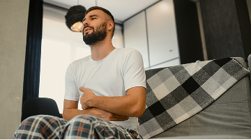 Man experiencing stomach ache and abdominal pain at home – digestive discomfort concept