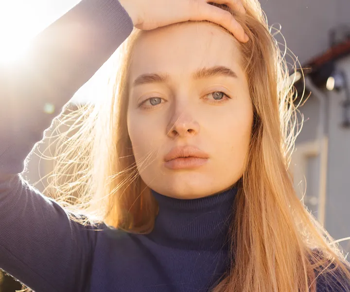 Person with wavy hair in sunlight wearing a navy turtleneck