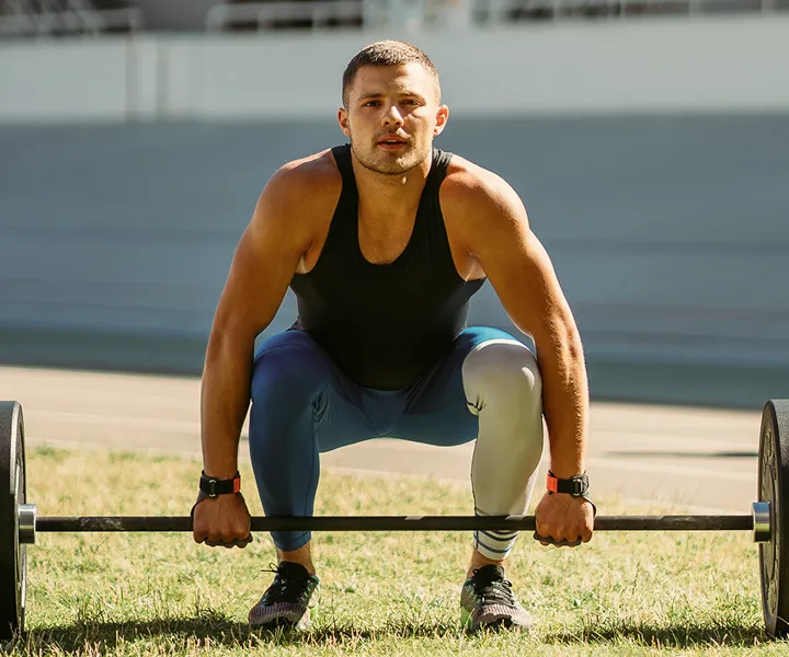 Person doing barbell squat on grassy field