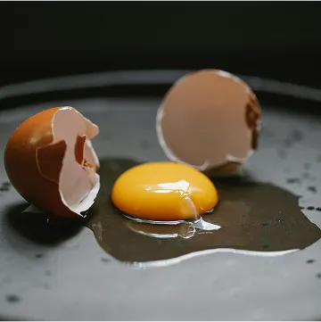 a broken egg lies on black plate