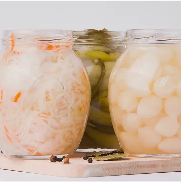 three jars of pickled vegetables on a wooden cutting board