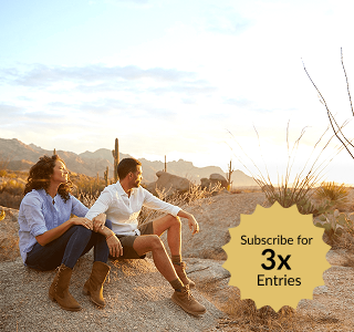 Couple sitting on desert rocks at sunset with mountain and cactus landscape in the background