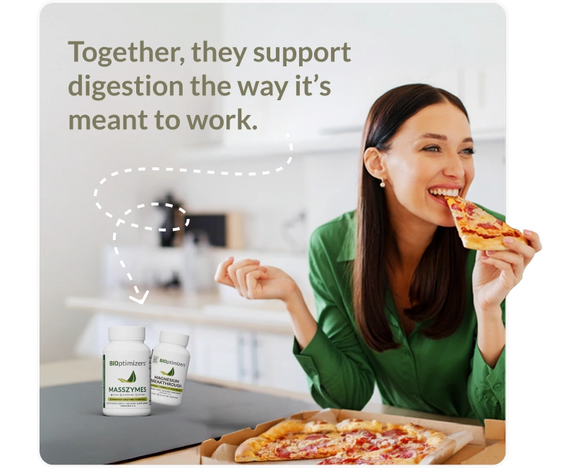 Woman enjoying pizza in a bright kitchen, representing healthy digestion with BiOptimizers MassZymes and Magnesium Breakthrough supplement bottles